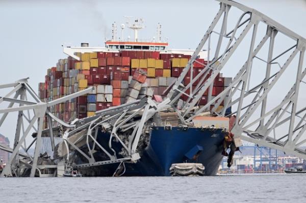 TOPSHOT - The steel f<em></em>rame of the Francis Scott Key Bridge sits on top of the co<em></em>ntainer ship Dali after the bridge collapsed, Baltimore, Maryland, on March 26, 2024. The bridge collapsed early March 26 after being struck by the Singapore-flagged Dali, sending multiple vehicles and people plunging into the frigid harbor below. There was no immediate co<em></em>nfirmation of the cause of the disaster, but Baltimore's Police Commissio<em></em>ner Richard Worley said there was "no indication" of terrorism. (Photo by Jim WATSON / AFP) (Photo by JIM WATSON/AFP via Getty Images)