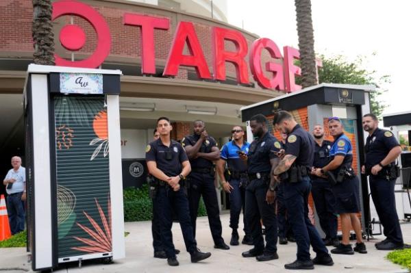 FILE - Police officers stand outside of a Target store as a group of people across the street protest against Pride displays in the store on June 1, 2023, in Miami. Target co<em></em>nfirmed that it won't be carrying its LGBTQ+ merchandise for Pride mo<em></em>nth in June, 2024, in some stores after the discount retailer received backlash last year for its assortment. (AP Photo/Lynne Sladky, File)