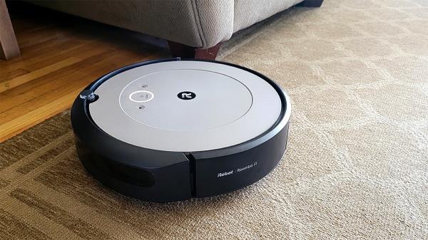 Roomba vacuuming carpet moving toward hardwood flooring