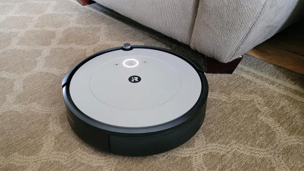 Roomba vacuuming carpet next to furniture