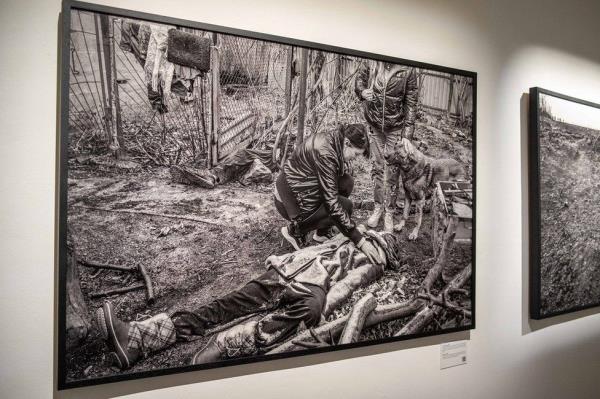 A display of a photo showing a woman next to the body of her brother in Bucha