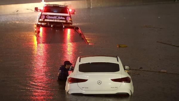 A tow truck driver attempts to pull a stranded car out of floodwaters on the Golden State Freeway as tropical storm Hilary moves through the area on August 20, 2023 in Sun Valley, California.