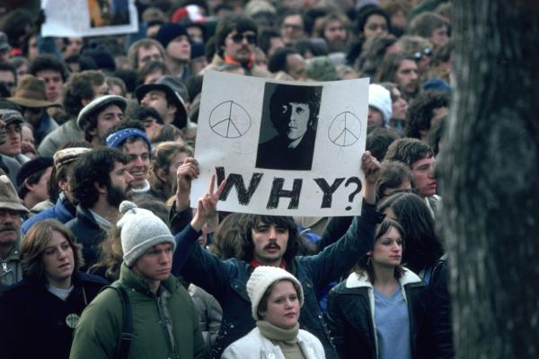 A crowd of people with a man holding a sign saying 