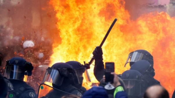 Flames from a fire rise behind law enforcement officers during a demo<em></em>nstration against the French government's pension reform plan as part of the fourth day of natio<em></em>nal protests, in Paris, France, February 11, 2023. REUTERS/Yves Herman