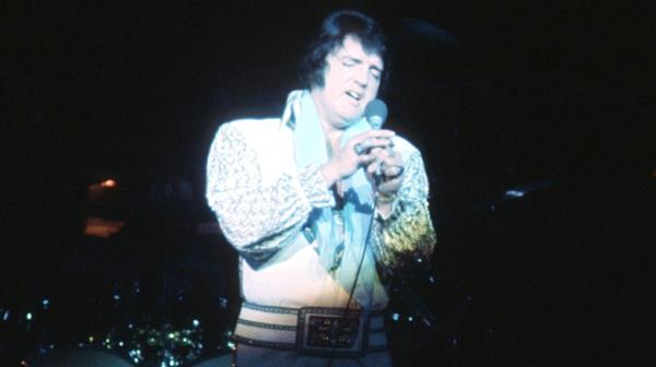 Elvis o<em></em>nstage in white suit with microphone