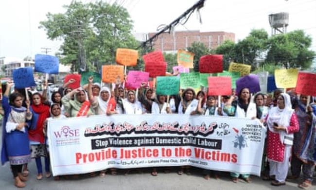 A line of women in a street holding placards and a banner that reads: 'Stop violence against domestic child labour - Provide justice to the victims'.   