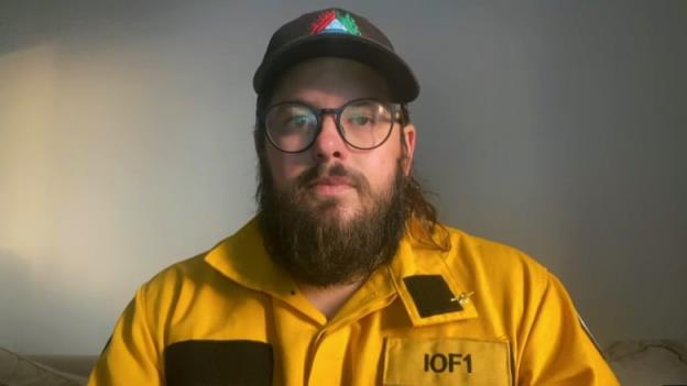 A man in a yellow fire fighting jacket poses for a picture. 