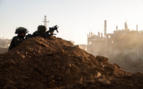 Two IDF soldiers use a mound of dirt as cover