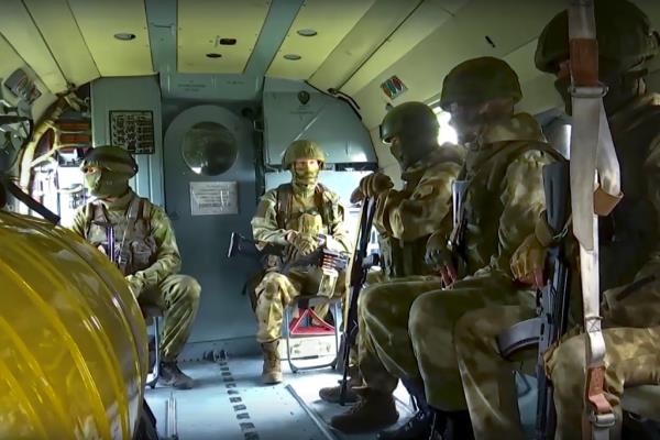 A group of Russian soldiers wearing camouflage uniforms and holding rifles inside an aircraft.