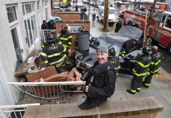 man holds camera with firefighters nearby