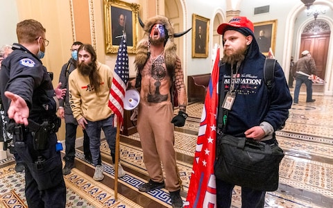 Chansley, centre, is co<em></em>nfronted by Capitol Police officers outside the Senate Chamber in Washington