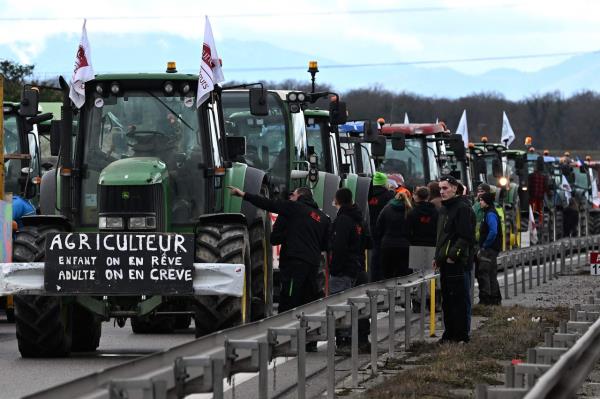 French farmers stand next to their tractors as they block the road, during a demo<em></em>nstration at the French-German border in Ottmarshe, eastern France, on Friday, as part of natio<em></em>nwide protests called by several farmers' unio<em></em>ns over pay, tax and regulations. (AFP)