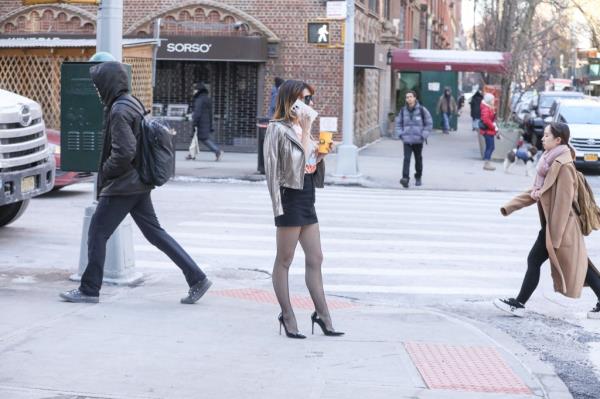 Hilaria Baldwin standing on a Manhattan sidewalk outside her apartment building while talking on the phone.