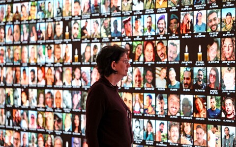 Raquel Ukeles, Head of Collections at Israel's Natio<em></em>nal Library, looks at a giant backlight screen bearing the portraits of Israelis who were killed