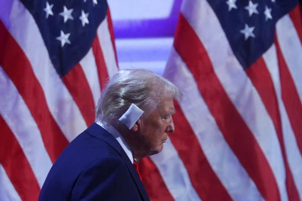 Do<em></em>nald Trump exits the stage with a backdrop of American flags and a bandage over his right ear.