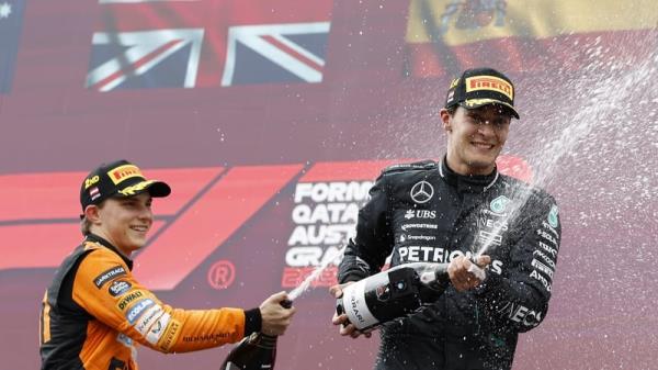 George Russell (R) and Lando Norris' McLaren team-mate Oscar Piastri celebrate on the podium