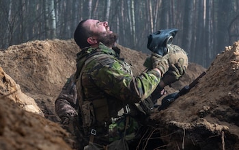 A soldier of the Natio<em></em>nal Guard of Ukraine takes off his gas mask and breathes fresh air after training with simulated smoke