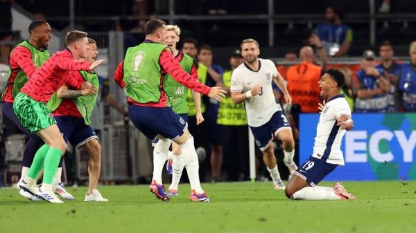 Players on the England bench rush to celebrate with Ollie Watkins after his late goal