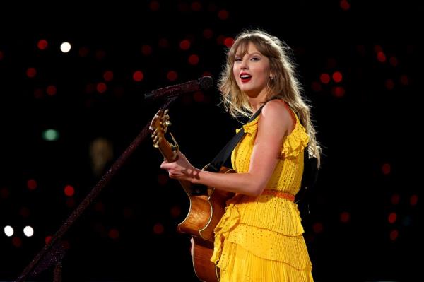 Taylor Swift performing o<em></em>nstage at Melbourne Cricket Ground in a yellow dress while playing guitar