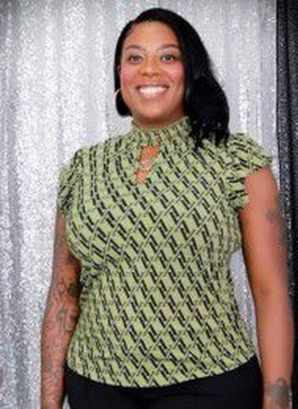 A black woman in a green and black shirt with tattoos on her arms