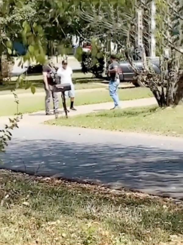 A man in a white shirt and brown ba<em></em>seball cap is arrested outside his house