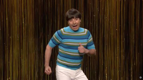 Jimmy Fallon in a bowl cut wig, dancing. 