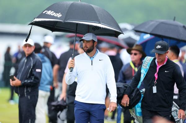 Scottie Scheffler of the United States and his caddie, Ted Scott, walk on the driving range 