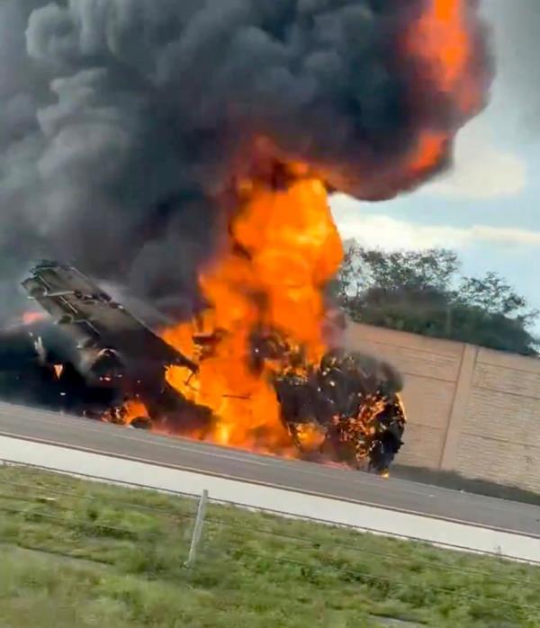 Video posted on social media shows the aircraft completely engulfed in flames in the middle of the southbound lane, spewing black smoke as halted drivers look on.