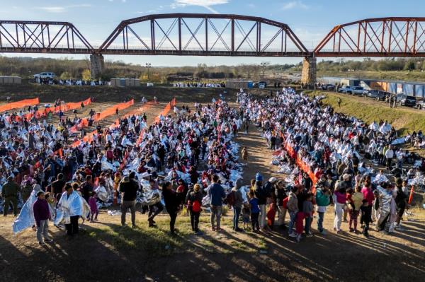 In an aerial view, thousands of immigrants, most wearing thermal blankets, await processing at a U.S. Border Patrol transit center on December 19, 2023 in Eagle Pass, Texas.