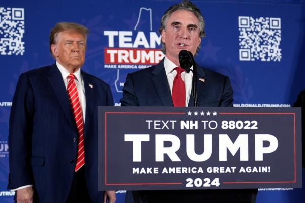 Former President Do<em></em>nald Trump listening to North Dakota Governor Doug Burgum speak at a campaign event on stage in Laconia, N.H., 2024