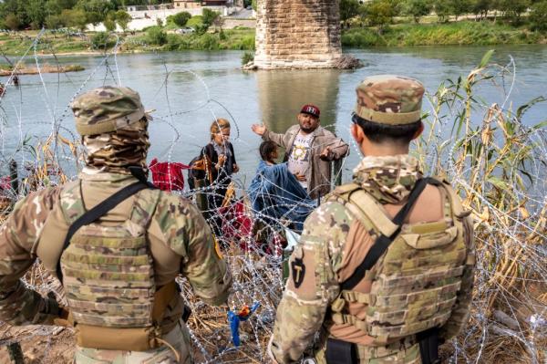 Texas Natio<em></em>nal Guard troops speak with a Venezuelan migrant after he crossed the Rio Grande from Mexico into the US.