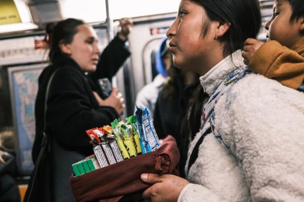 A woman with a small child sells candy in the D train in Manhattan