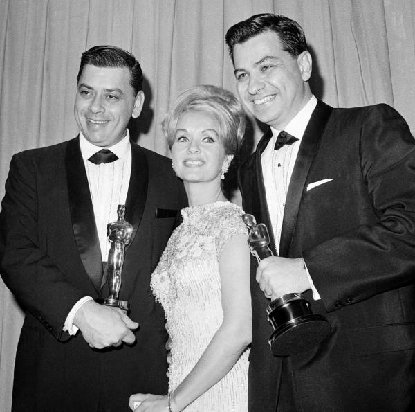 In this April, 5,1965 file photo actress Debbie Reynolds poses with Academy Awards winners for best music Richard M. Sherman, right, and Robert Sherman, left,