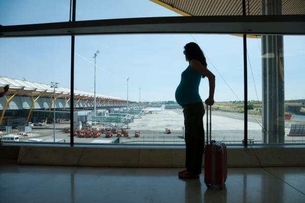 Woman pregnant silhouette waiting to fly in airport hall.