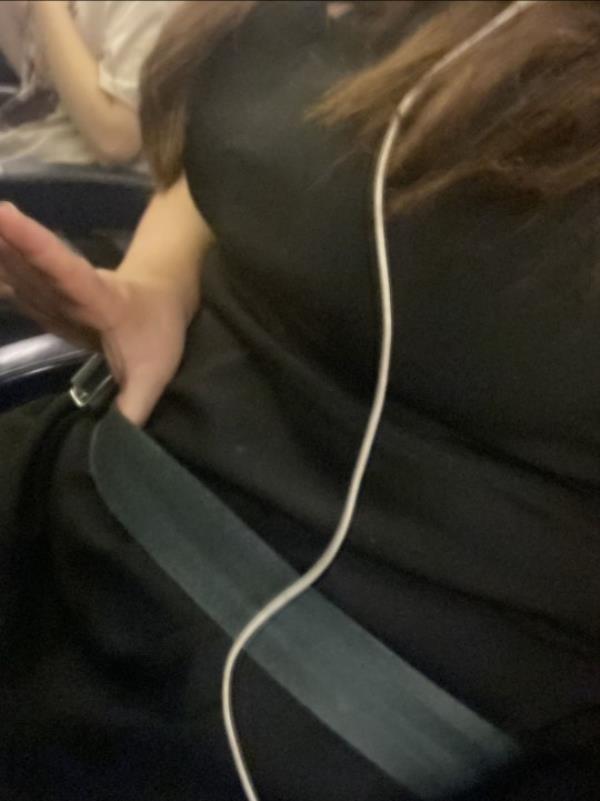 A close up of a woman fastening a seatbelt on a plane. 