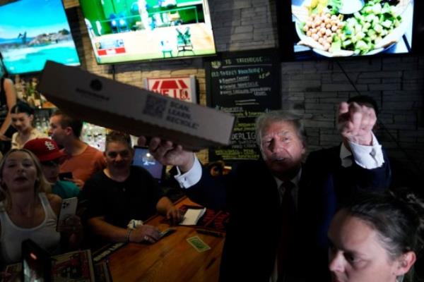 Former President Do<em></em>nald Trump serves pizza to supporters at the Treehouse Pub & Eatery, Wednesday, Sept. 20, 2023, in Bettendorf, Iowa. (AP Photo/Charlie Neibergall)