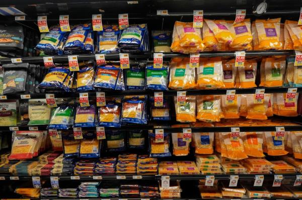 Cheese products in plastic packaging line the cooler at a grocery store