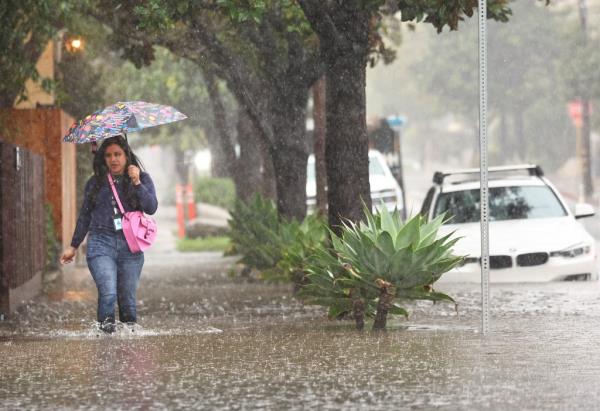 A woman walking on a flooded sidewalk in Santa Barbara, California during an atmospheric river storm on Feb. 4, 2024.