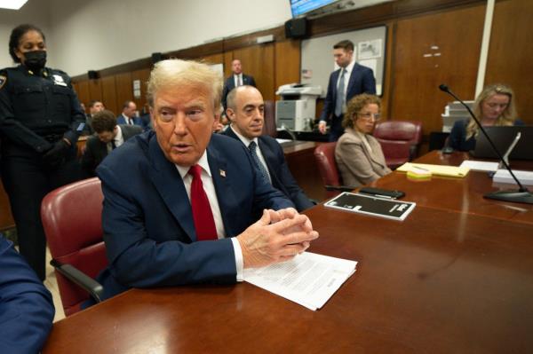 Former President Do<em></em>nald Trump sitting at a table in Manhattan criminal court, with people in the background, on May 16, 2024.