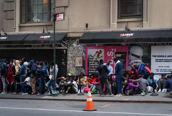 Asylum seekers fill the sidewalk outside of the Roosevelt hotel in midtown Manhattan, New York City.