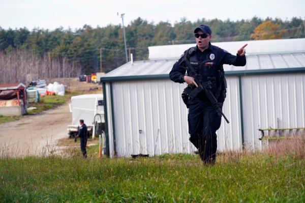  A police officer gives an order to the public during the manhunt for Robert Card.