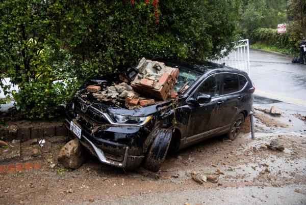 Bricks lie on top of a damaged car, during the o<em></em>ngoing rain storm