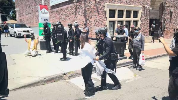 LAPD officers in full riot gear were seen approaching two people inside a Range Rover at a gas station across from the house of worship with guns drawn.