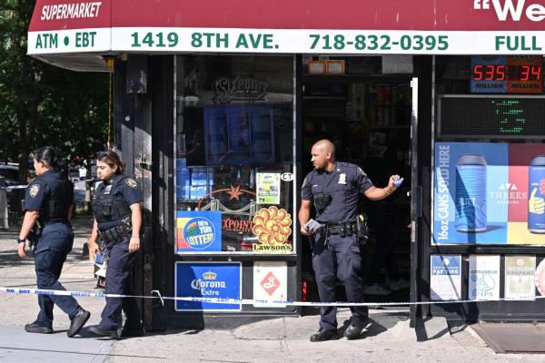 Two police officers standing outside a deli in South Slope, Brooklyn wher<em></em>e a man was shot during a botched robbery