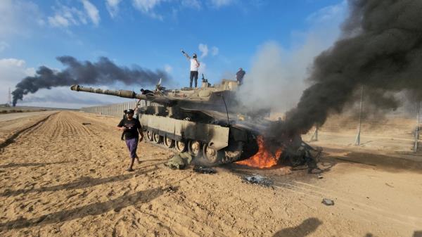 Palestinians celebrating on a destroyed Israeli tank  at the Gaza Strip border near Khan Younis.