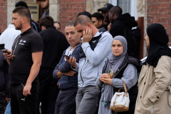 People stand near the Lycee Gambetta-Carnot high school after a teacher was killed and several people injured in a knife attack in Arras, northern France, October 13, 2023. REUTERS/Pascal Rossignol