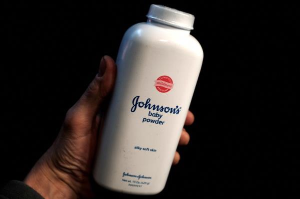 A hand holding a white bottle of Johnson & Johnson Baby Powder in New York