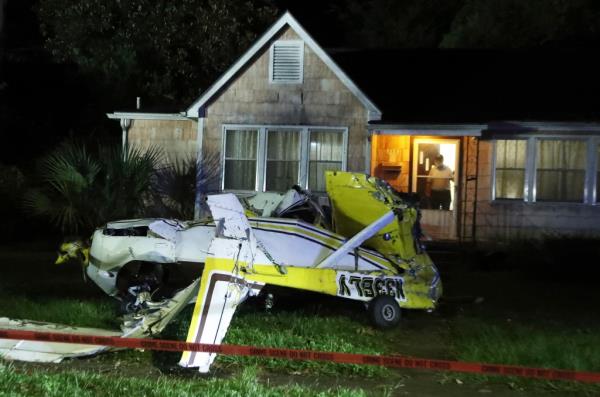 A man looking out his front door at a crashed Cessna in his front yard in Savannah, Georgia