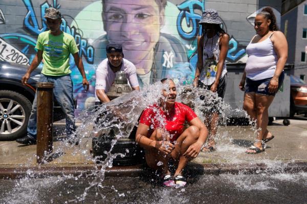 Jennifer Pagan reacting to the cool spray of an open fire hydrant during a heat wave in The Bronx, New York, July 22, 2022