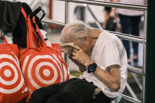 Man dabbing his face with a napkin in Unio<em></em>n Square subway station during a hot day